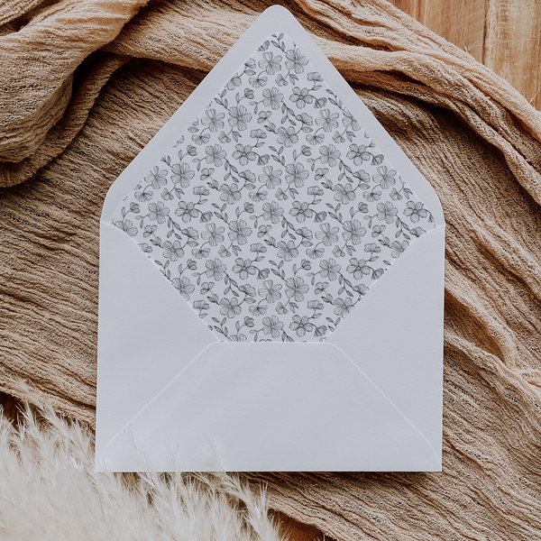 A flat lay of elegant wedding invitation envelopes, partially open to reveal beautifully designed envelope liners in various styles, including floral, modern, and classic patterns. The envelope inserts add a touch of luxury and sophistication to the stationery set.