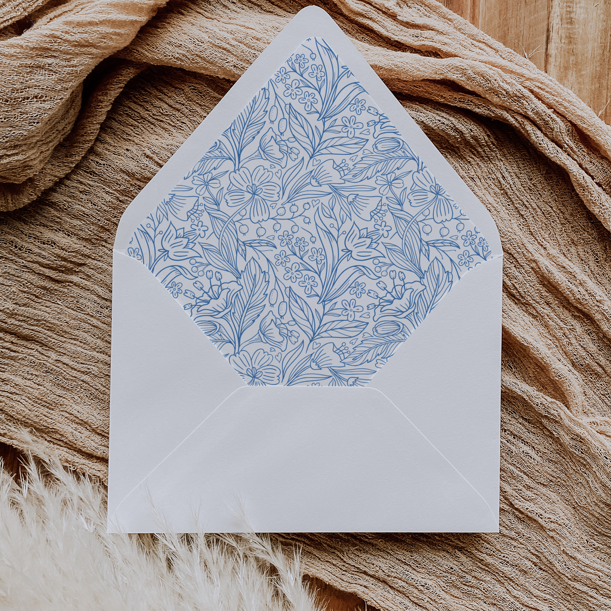 A flat lay of elegant wedding invitation envelopes, partially open to reveal beautifully designed envelope liners in various styles, including floral, modern, and classic patterns. The envelope inserts add a touch of luxury and sophistication to the stationery set.
