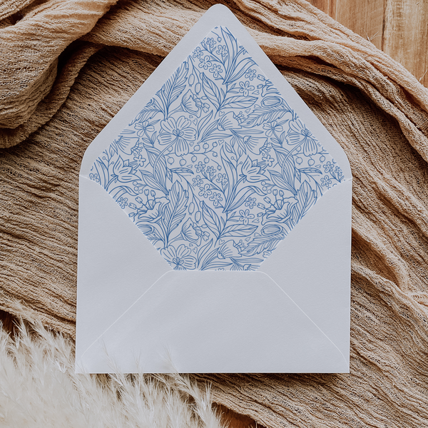 A flat lay of elegant wedding invitation envelopes, partially open to reveal beautifully designed envelope liners in various styles, including floral, modern, and classic patterns. The envelope inserts add a touch of luxury and sophistication to the stationery set.