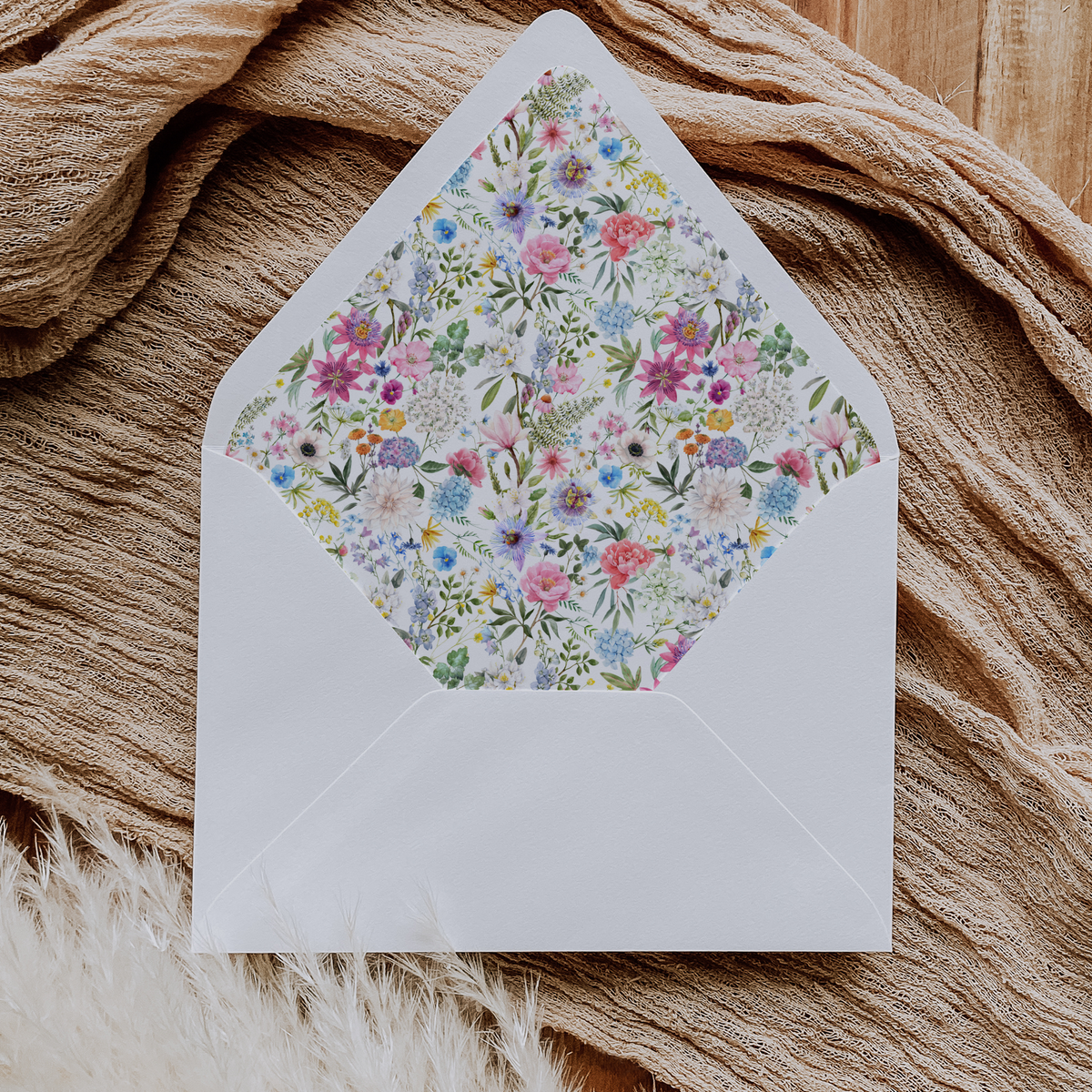 A flat lay of elegant wedding invitation envelopes, partially open to reveal beautifully designed envelope liners in various styles, including floral, modern, and classic patterns. The envelope inserts add a touch of luxury and sophistication to the stationery set.
