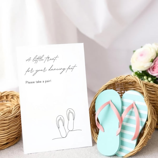A stylish wedding sign reading "A little treat for your dancing feet, please take a pair", displayed next to a basket of flip-flops for guests. The design features elegant typography, perfect for a wedding reception.