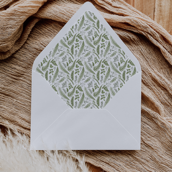 A flat lay of elegant wedding invitation envelopes, partially open to reveal beautifully designed envelope liners in various styles, including floral, modern, and classic patterns. The envelope inserts add a touch of luxury and sophistication to the stationery set.