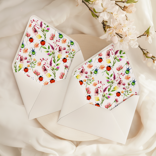 A flat lay of elegant wedding invitation envelopes, partially open to reveal beautifully designed envelope liners in various styles, including floral, modern, and classic patterns. The envelope inserts add a touch of luxury and sophistication to the stationery set.
