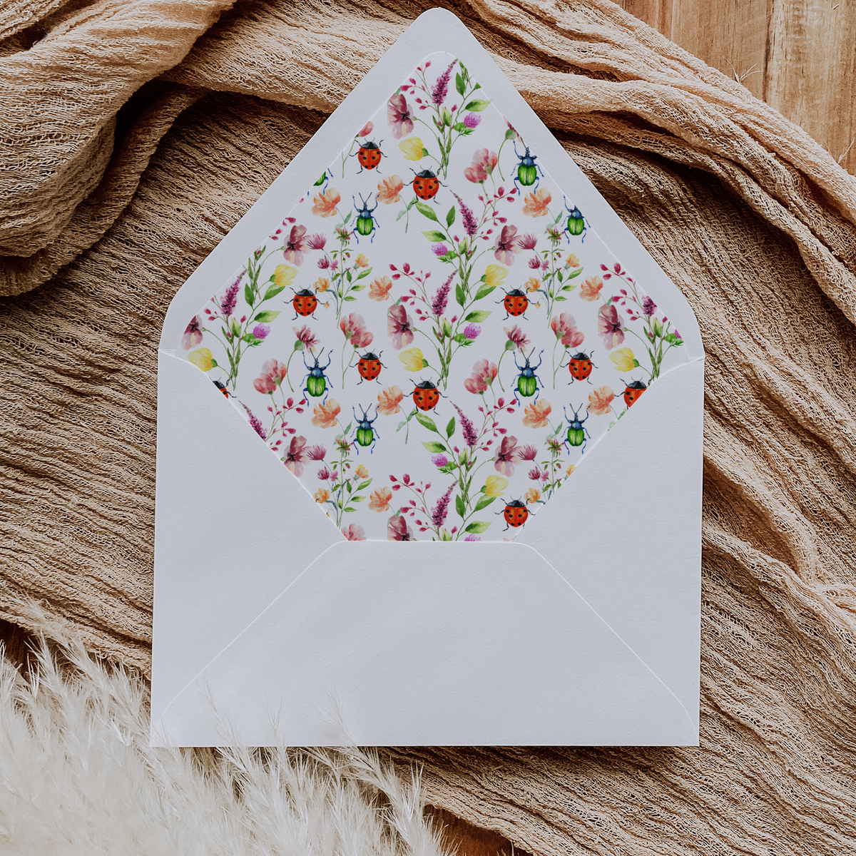 A flat lay of elegant wedding invitation envelopes, partially open to reveal beautifully designed envelope liners in various styles, including floral, modern, and classic patterns. The envelope inserts add a touch of luxury and sophistication to the stationery set.