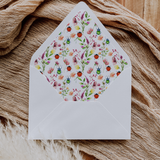 A flat lay of elegant wedding invitation envelopes, partially open to reveal beautifully designed envelope liners in various styles, including floral, modern, and classic patterns. The envelope inserts add a touch of luxury and sophistication to the stationery set.
