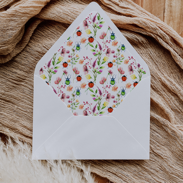 A flat lay of elegant wedding invitation envelopes, partially open to reveal beautifully designed envelope liners in various styles, including floral, modern, and classic patterns. The envelope inserts add a touch of luxury and sophistication to the stationery set.