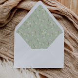 A flat lay of elegant wedding invitation envelopes, partially open to reveal beautifully designed envelope liners in various styles, including floral, modern, and classic patterns. The envelope inserts add a touch of luxury and sophistication to the stationery set.