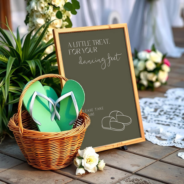A stylish wedding sign reading "A little treat for your dancing feet, please take a pair", displayed next to a basket of flip-flops for guests. The design features elegant typography, perfect for a wedding reception.