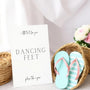 A stylish wedding sign reading "A little treat for your dancing feet, please take a pair", displayed next to a basket of flip-flops for guests. The design features elegant typography, perfect for a wedding reception.