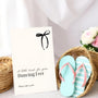 A stylish wedding sign reading "A little treat for your dancing feet, please take a pair", displayed next to a basket of flip-flops for guests. The design features elegant typography, perfect for a wedding reception.