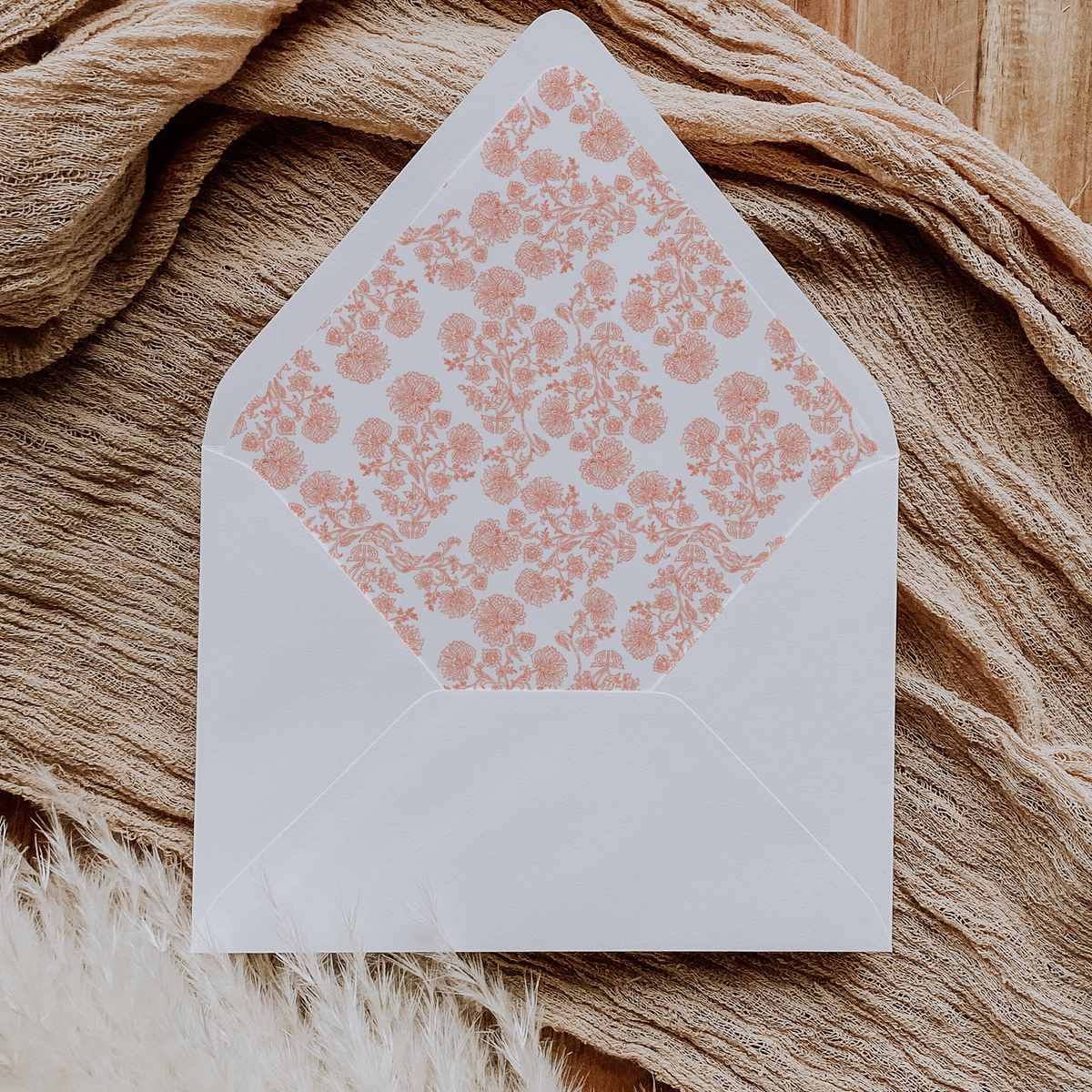 A flat lay of elegant wedding invitation envelopes, partially open to reveal beautifully designed envelope liners in various styles, including floral, modern, and classic patterns. The envelope inserts add a touch of luxury and sophistication to the stationery set.