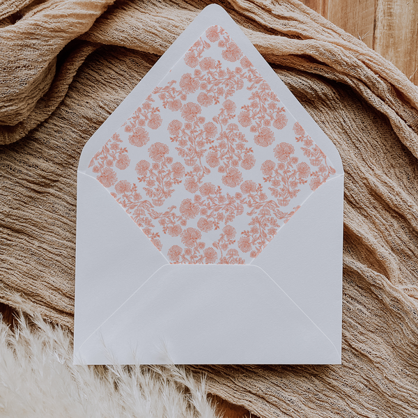 A flat lay of elegant wedding invitation envelopes, partially open to reveal beautifully designed envelope liners in various styles, including floral, modern, and classic patterns. The envelope inserts add a touch of luxury and sophistication to the stationery set.