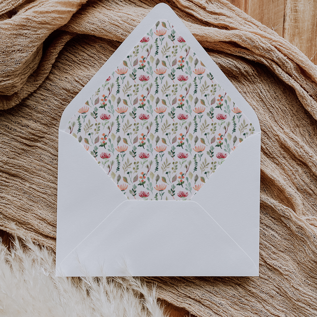 A flat lay of elegant wedding invitation envelopes, partially open to reveal beautifully designed envelope liners in various styles, including floral, modern, and classic patterns. The envelope inserts add a touch of luxury and sophistication to the stationery set.