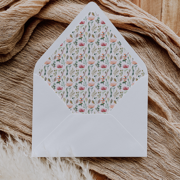 A flat lay of elegant wedding invitation envelopes, partially open to reveal beautifully designed envelope liners in various styles, including floral, modern, and classic patterns. The envelope inserts add a touch of luxury and sophistication to the stationery set.