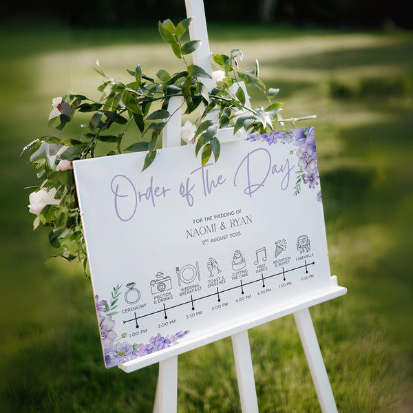 lilac floral order of the day board for weddings - a personalised order of events sign, with a crisp white background and sophisticated black text, adorned with lilac and lavender florals.
