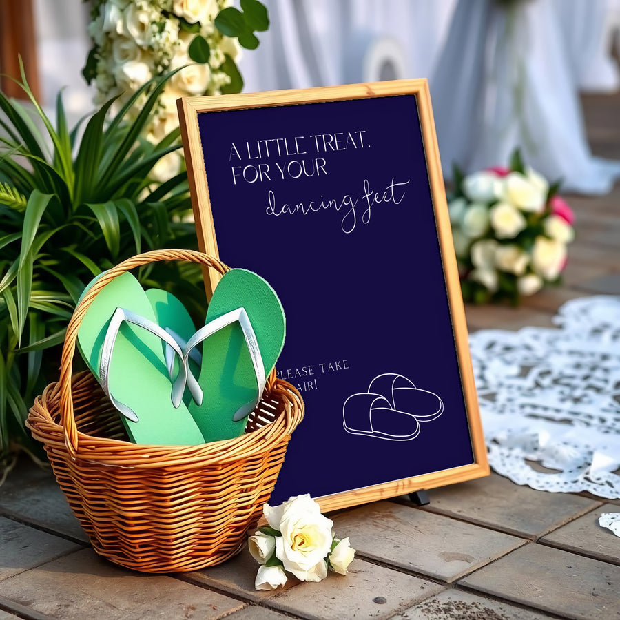 A stylish wedding sign reading "A little treat for your dancing feet, please take a pair", displayed next to a basket of flip-flops for guests. The design features elegant typography, perfect for a wedding reception.