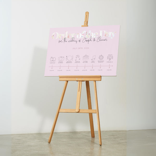 pastel pink wedding order of the day sign, with beautiful calligraphy text and a floral white header.