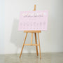 pastel pink wedding order of the day sign, with beautiful calligraphy text and a floral white header.