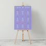 Purple seating chart on a wooden easel against a gray background