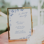 Santorini in loving memory wedding table sign with blue botanical sketches and elegant handwritten script