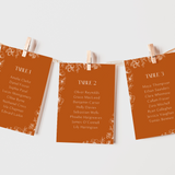 Toasted Amber wedding seating plan cards with burnt orange background and white botanical line art