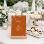Toasted Amber sweet table wedding sign with burnt orange background and white botanical line art