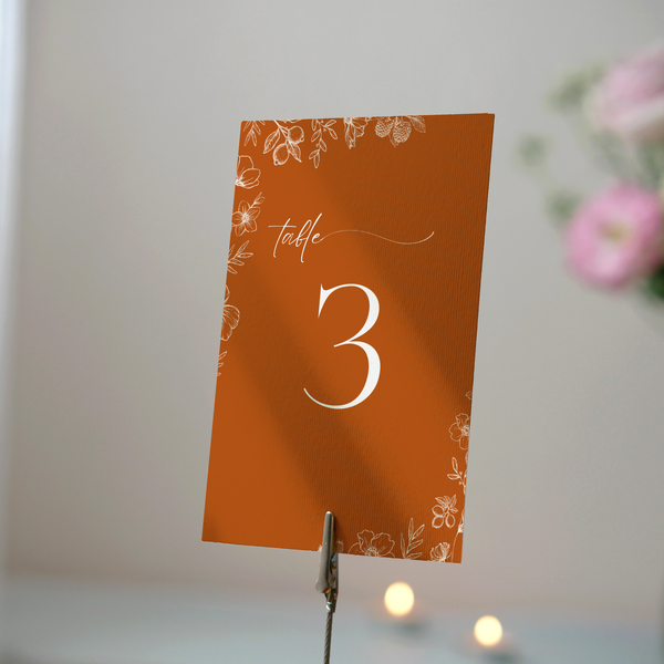 Toasted Amber wedding table number card with burnt orange background and white botanical line art