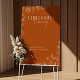 Toasted Amber unplugged ceremony wedding sign with burnt orange background and white botanical line art